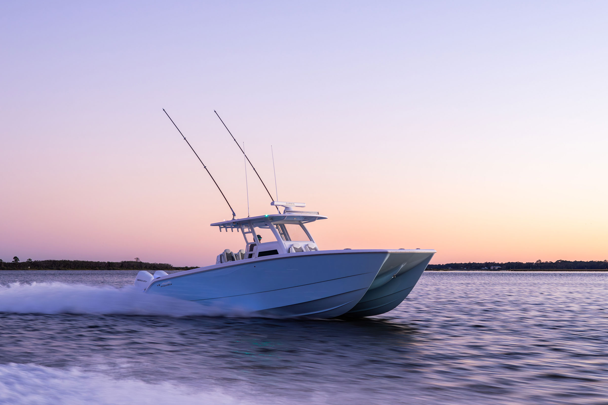 Invincible 38' Catamaran on the move with sunset behind it